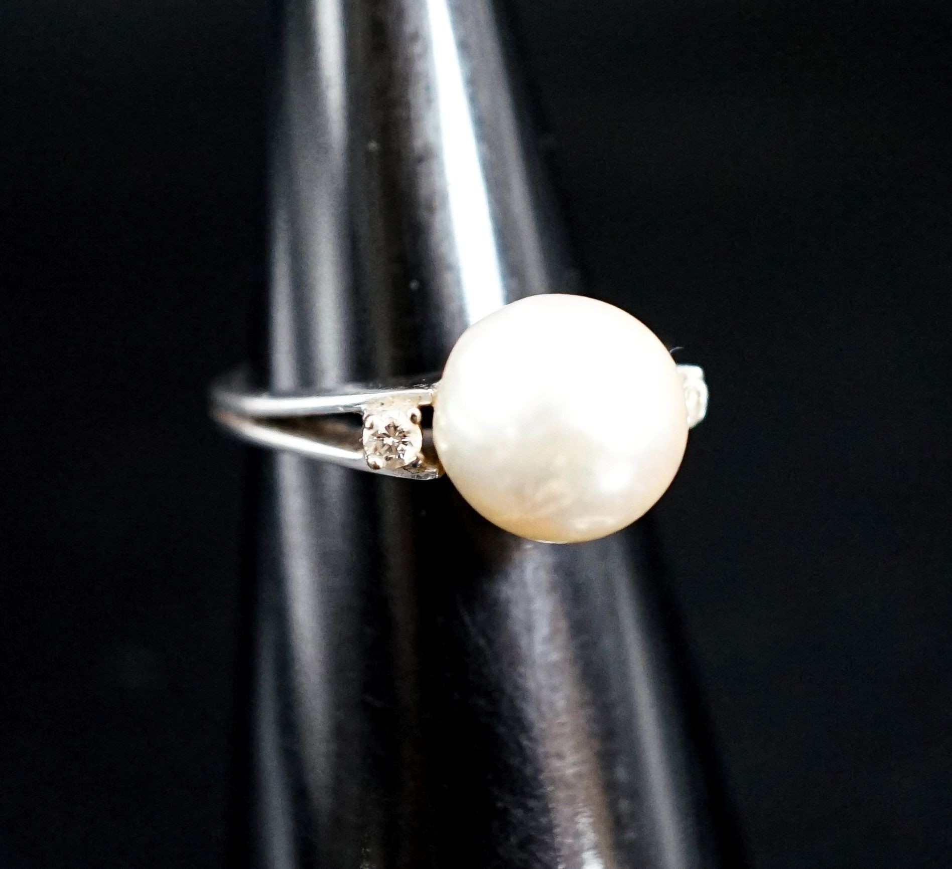 A white metal and single stone cultured pearl dress ring, with diamond set shoulders, size L/M, gross 4.1 grams.